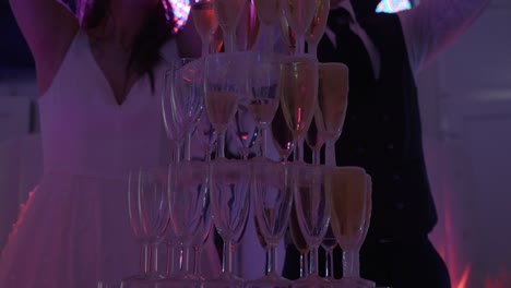 Bride-and-groom-filling-tower-of-glasses-at-their-wedding-party-with-champagne