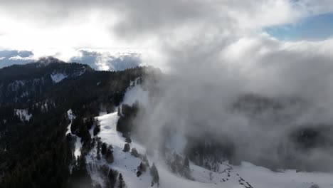 Flying-in-steam-clouds-over-snow-valley-with-pines,-Chartreuse,-French-Alps