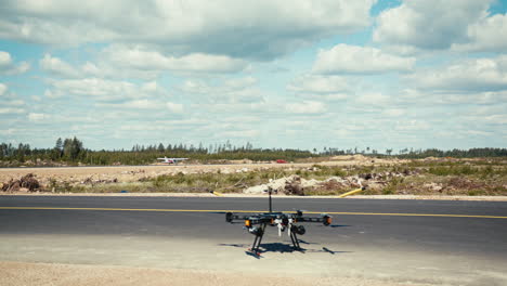 Professional-gasoline-powered-drone-preparing-for-departure-close-to-manned-aircraft-on-runway