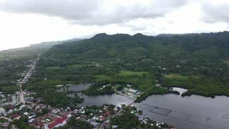 Panoramic-Wet-Lake-Around-Green-Fields-of-Anda-Village,-bohol-Philippines-Aerial-Drone-Town-Landscape-and-Skyline-View
