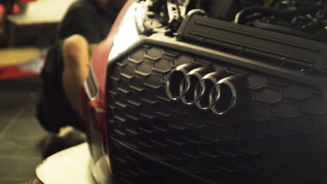 Right-side-pan-shot-of-the-front-end-logo-on-an-Audi-race-car-with-its-headlights-on