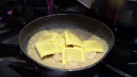 Adding-ravioli-and-cooking-shrimp-with-sour-cream-in-a-cooking-pan-in-slow-motion