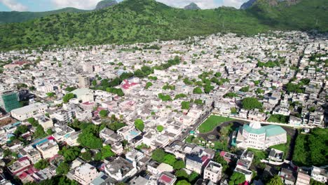 Plaine-verte-neighborhood-in-port-louis,-mauritius,-showcasing-dense-urban-housing-with-lush-green-hills-in-the-backdrop,-sunny-day,-aerial-view