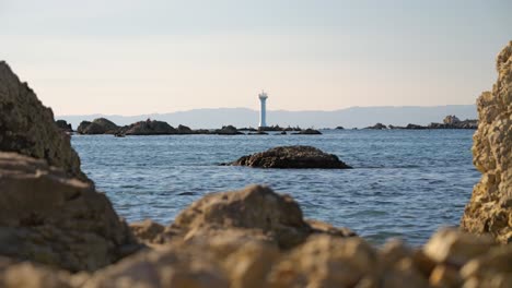 Beautifully-framed-view-out-on-lighthouse-between-rocks-with-ocean