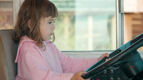 Active-Toddler-Girl-Turns-Steering-Wheel-of-Old-Bus-and-Beeping-While-Sitting-in-Driver's-Seat