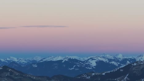 Drohnenaufnahmen-Zeigen-Die-ätherische-Schönheit-Des-Sonnenaufgangs,-Der-Die-Silhouette-Einer-Schneebedeckten-Bergkette-Erhellt