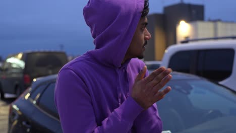 Young-Sri-Lankan-man-trying-to-warm-hands-while-standing-in-parking-lot
