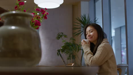 Young-pretty-Asian-girl-dreaming-and-smiling-in-cafe