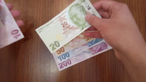 Ein-Teenager-Sortiert-Jede-Banknote-Der-Türkischen-Lira-Nach-Wert,-Mit-Einem-Porträt-Von-Mustafa-Kemal-Atatürk,-Dem-Gründer-Der-Republik-Türkei,-Obenauf