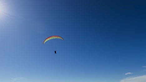 Three-para-gliders-flying-across-the-bright-sun-on-a-beautiful-day-at-Torrey-Pines-Gliderport-in-La-Jolla,-California