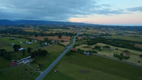 Chiloe-at-sunset-with-sweeping-landscapes-and-a-serene-highway,-aerial-view