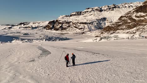 Aerial-landscape-view-over-two-people-on-a-expedition-on-Sólheimajökull-glacier,-climate-change,-in-Iceland