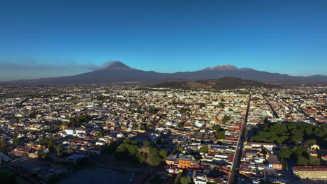Aerial-view-backwards-passing-the-Cholula-pyramid,-sunny-evening-in-Puebla,-Mexico