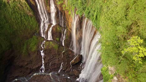 Tumpak-Sewu-waterfall,-the-majestic-cascade-plunging-over-lush-cliffs,-offering-a-breathtaking-sight-with-its-multiple-streams-flowing-like-a-curtain-of-mist