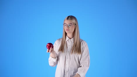 Caucasian-young-lady-plays-with-an-apple-in-smart-glasses-teacher-look-biting-the-fruit