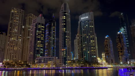 Toma-Panorámica-De-La-Vista-Nocturna-De-Los-Rascacielos-En-El-Puerto-Deportivo-De-Dubai:-Un-Barrio-Residencial-Y-Un-Distrito-En-Dubai.