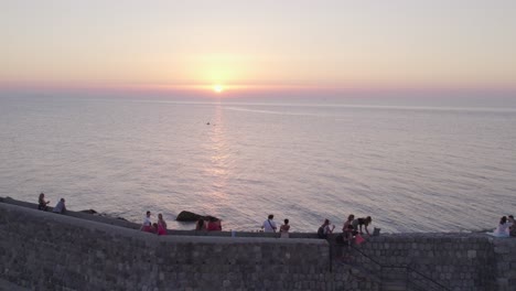 Luftaufnahme-Eines-Bootes-Auf-Ruhiger-See-Mit-Menschen-Bei-Sonnenuntergang,-Cefalu,-Sizilien,-Italien