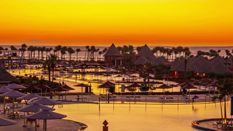 Aerial-Sunset-Landscape-Gradient-Colorful-Egypt-Skyline-Vibes,-Palm-Trees-Water-Pool-Lake-by-Coastline-Street,-Vehicles-Drive-By,-Reflected-Lake-Sharm-El-Sheikh