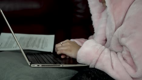 Person-Wearing-Pink-bathrobe-Scrolling-On-Touchpad-On-Laptop