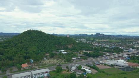 Scenic-Aerial-Drone-Over-Expressway-with-Hillside-Clock-Tower-in-Thailand-near-Khao-Kaen-Chan-Temple