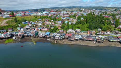 Drones-Aéreos-Vuelan-Sobre-La-Costa-De-Las-Casas-Del-Cielo-De-La-Isla-Chilena-Patagónica-De-Chiloé-Y-La-Orilla-De-La-Playa,-Horizonte-De-Luz-Diurna-En-Destino-De-Viaje-Sudamericano