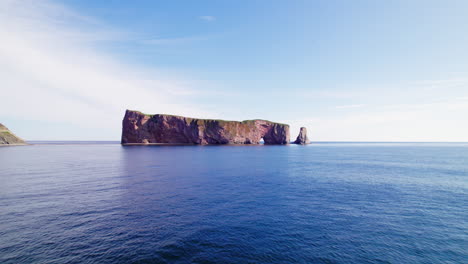 Drone-forward-tracking-shot-of-Percé-Rock-above-the-Saint-Lawrence-River-during-a-sunny-day