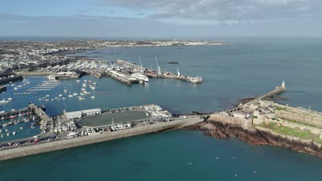 St.-Peter-Port-Guernsey-Flug-In-Richtung-Fährterminal-Mit-Fähre-Im-Dock,-über-Havelet-Bay,-Castle-Breakwater-Und-Marinas-Mit-Blick-über-Belle-Greve-Bay-An-Einem-Hellen,-Sonnigen-Tag-Mit-Klarem-Meer-Und-Blauem-Himmel
