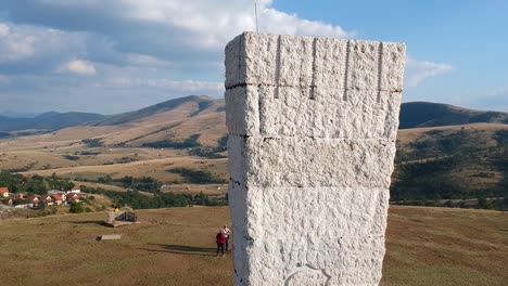 Monumento-A-Los-Partisanos-Ejecutados-De-Zlatibor-Serbia,-Drone-Dolly-En-Toma-Que-Revela-Hermosas-Montañas-En-El-Fondo-Con-Las-Nubes-Esponjosas-Arriba