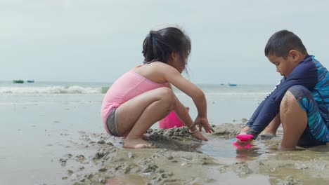 Two-Asian-children-playing-on-the-sand-at-a-beautiful-beach