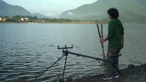 Un-Hombre-Vestido-De-Verde-Espera-Pacientemente-El-Momento-De-Lanzar-Su-Caña-A-Las-Tranquilas-Aguas-Del-Lago-Kawaguchiko-En-Yamanashi,-Japón.