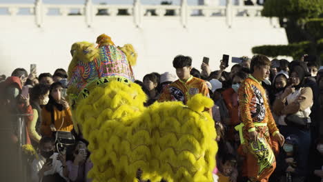 Crowd-watches-vibrant-Chinese-lion-dance-performance-in-Taipei,-sunlight-casting-shadows