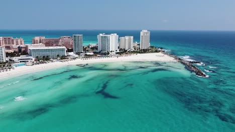 Cancun's-coastline-with-clear-turquoise-waters-and-bustling-beachfront-hotels,-aerial-view