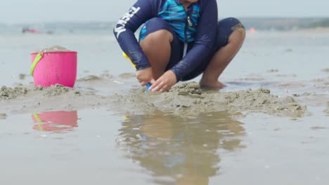 Dos-Niños-Asiáticos-Jugando-En-La-Arena-De-Una-Hermosa-Playa