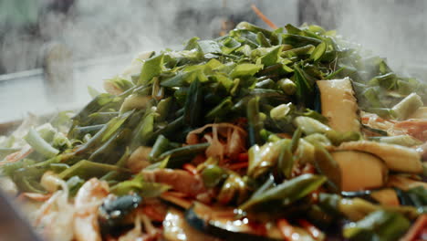 Soy-sauce-pouring-on-steaming-hot-vegetables-on-grill