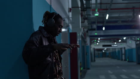 Afro-American-black-musician-rapper,-wearing-headphone-in-underground-parking-garage,-makes-cool-moves-to-the-beat-of-music-in-his-headphones