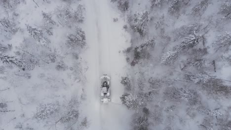Draufsicht-Auf-Einen-Traktor,-Der-Dicken-Schnee-Auf-Einer-Winterlichen-Landstraße-Entfernt