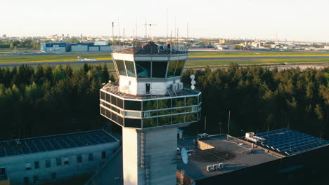Luftaufnahme-Des-Kontrollturms-Des-Flughafens-Tallinn-Im-Frühen-Sonnenuntergang-Mit-Finnair-Norra-ATR-72-Turboprop-Auf-Der-Landebahn-Im-Hintergrund