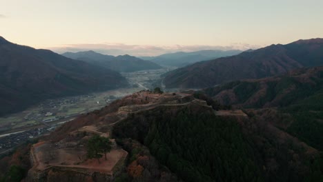 Aerial-Japanese-Mountain-Range-Valley-in-Takeda-Castle-ruins-Asago-Hyogo-Deep-Mountain-Range-with-Sunset-Skyline,-gradient,-aerial-drone-establishing-Japan-Travel