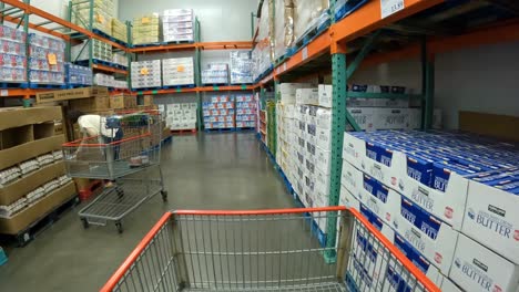POV---At-the-local-Costco,-slowly-pushing-cart-in-the-refrigerated-room-containing-bulk-containers-of-milk,-almond-milk,-butter-and-creamer