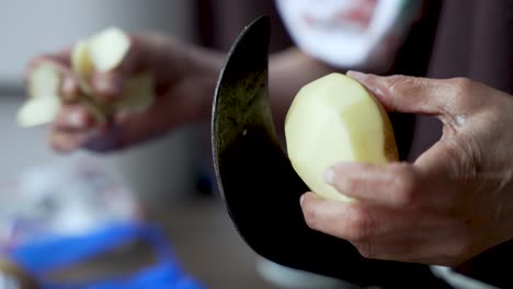 Close-up-of-aged-hands-peeling-a-potato-with-a-traditional-Indian-Aruvamanai-cutter