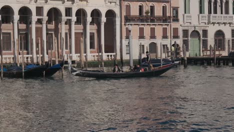 Gondola-glides-on-waterway-with-tourists-exploring-Venice