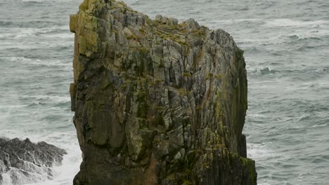 Giant-natural-rock-stack-with-the-ocean-breaking-against-the-cliff-face-in-the-background,-along-the-coastline-of-Lewis-Island-in-the-Outer-Hebrides-of-Scotland