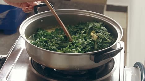 Mixing-and-stirring-moringa-leaves-or-malunggay-to-cook-ginataang-gulay-or-coconut-milk-vegetable-stew,-a-vegan-traditional-Filipino-dish