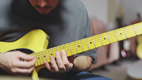 Primer-Plano-De-Un-Músico-Experto-Que-Toca-La-Guitarra-Amarilla-Stratocaster-En-El-Estudio