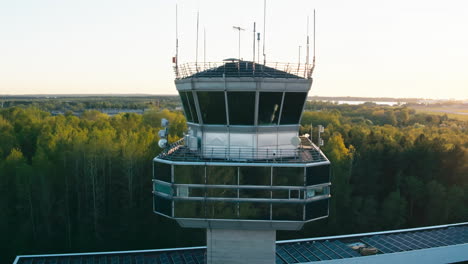 Luftaufnahme-Des-Kontrollturms-Des-Flughafens-Tallinn-Im-Gelben-Sommersonnenuntergang-Mit-Terminal-Und-Landebahn-Im-Hintergrund