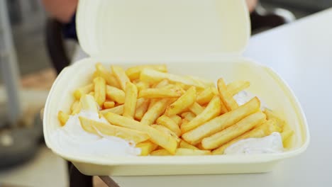 La-Mano-De-Una-Mujer-Abre-Un-Recipiente-De-Plástico-Con-Deliciosas-Patatas-Fritas-En-Su-Interior.