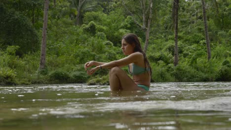 Woman-in-bikini-enjoying-a-serene-river-in-a-lush-Philippine-jungle,-midday,-tranquil-mood,-static-shot