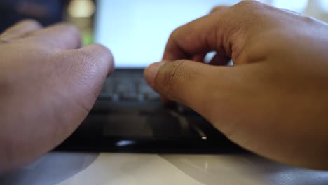 Hands-typingon-a-laptop,-blurred-background,-close-up,-indoor-setting