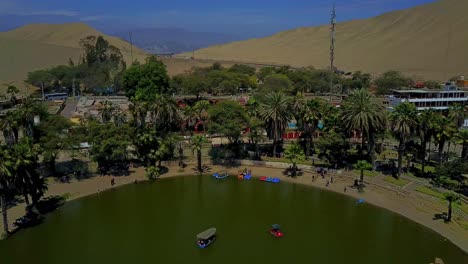 Aerial-Shot-Over-Huacachina-Oasis-in-the-Desert-with-a-Slow-Tilt-Up-Shot-Along-the-Water's-Edge-with-Palm-Trees