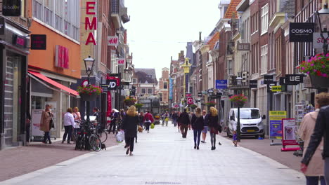 Pedestrians-strolling-through-shopping-street-in-The-Netherlands,-sunny-day